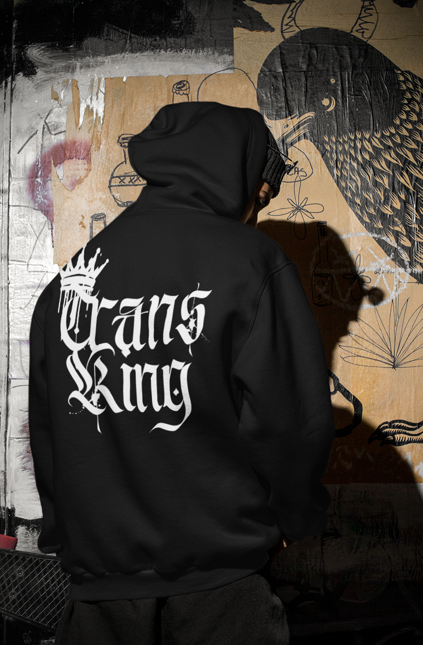 Grunge background with someone in a Black Hoodie with Trans King written in gothic font and spray paint crown for trans pride and trans joy