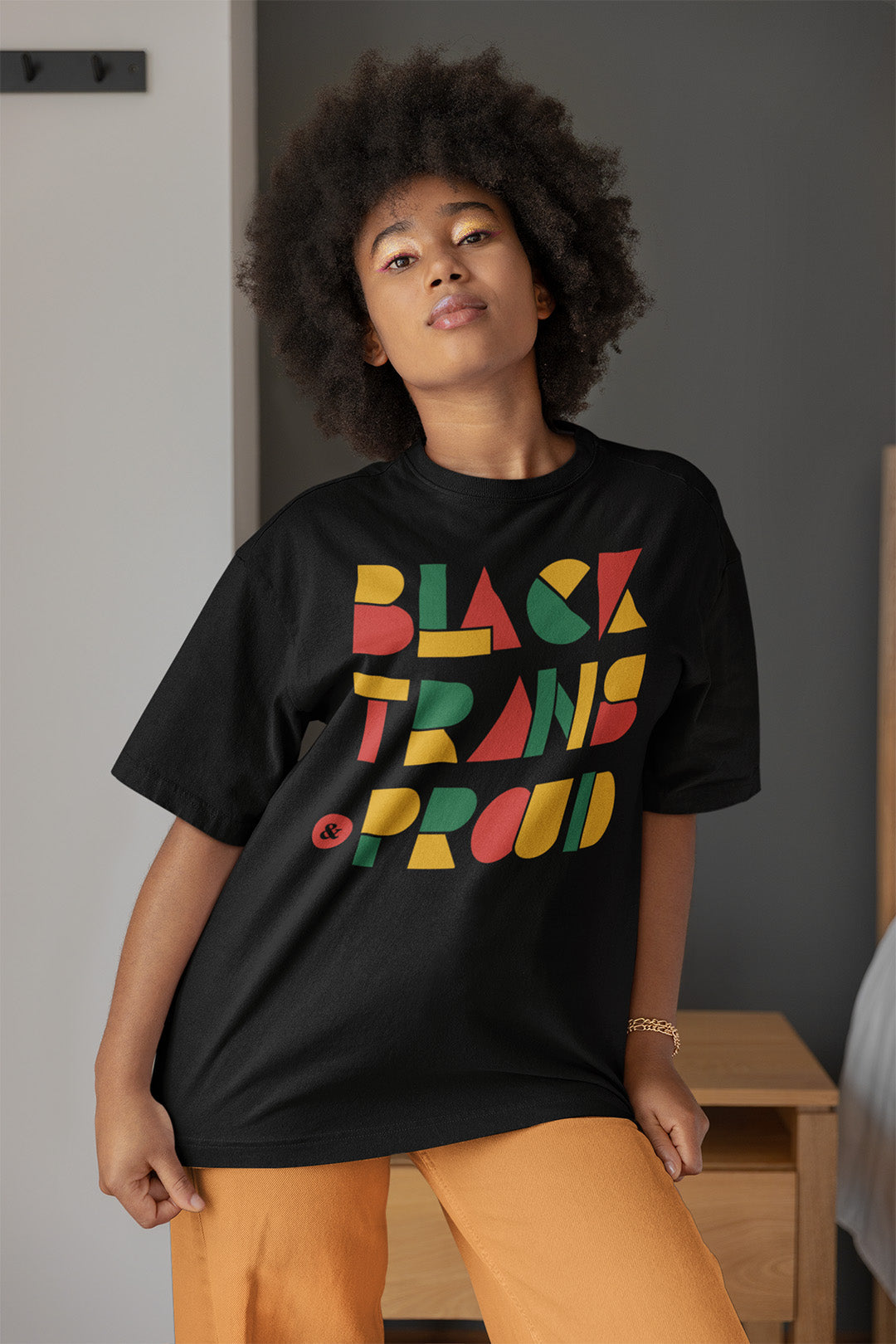 Black woman with fro in a black oversized tee with geometric lettering saying BlaQ Pride in red, yellow and green for Queer Pride and Black Pride T Shirt