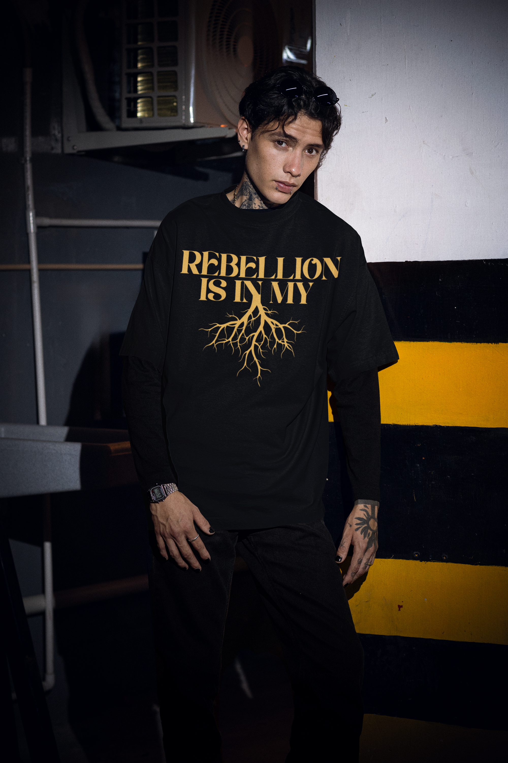 Pride T Shirts Tattooed Man with Black Oversized Tee with striking yellow text Rebellion is in my Roots with roots graphic as a protest tee