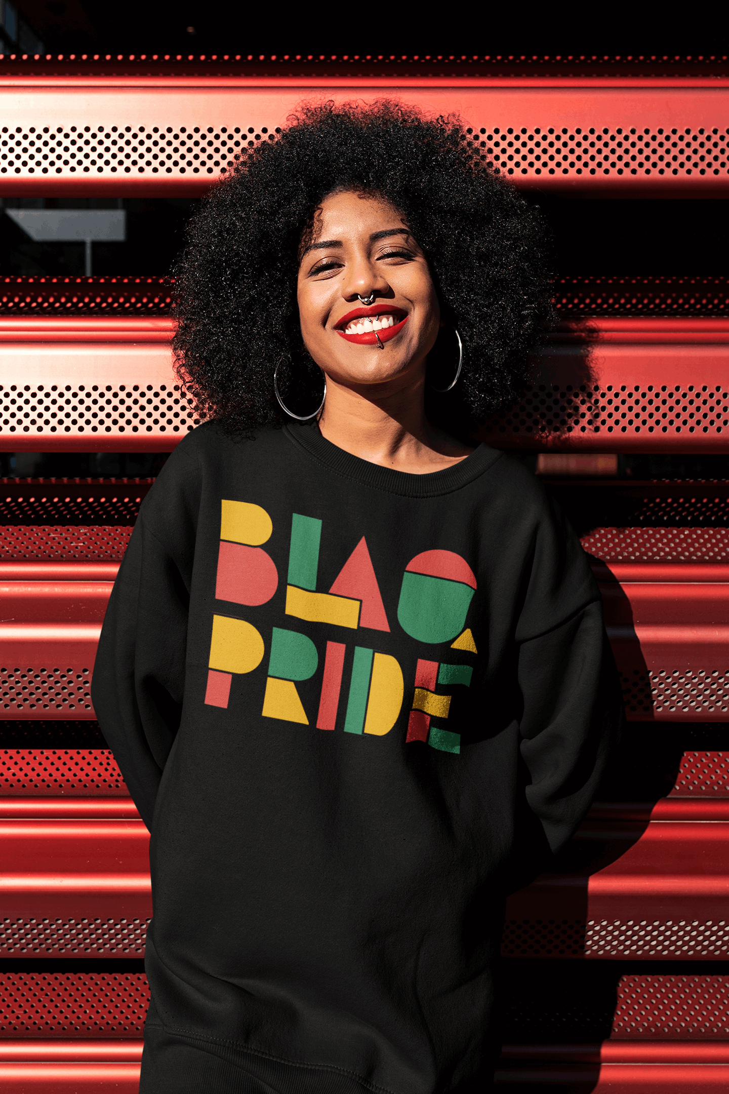 Black woman with fro in a black oversized tee with geometric lettering saying BlaQ Pride in red, yellow and green for Queer Pride and Black Pride T Shirt