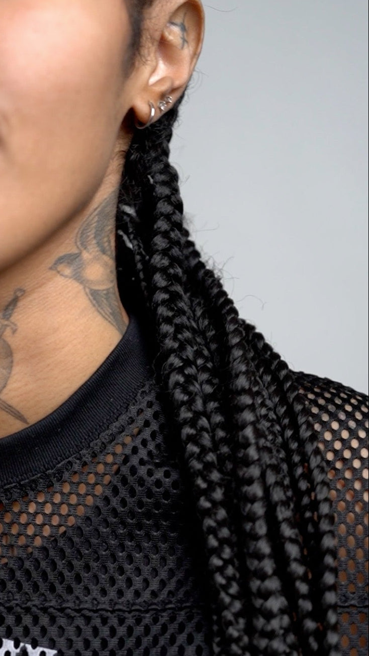 Person wearing a black mesh top with text, close-up of neck and shoulder area where the collar is