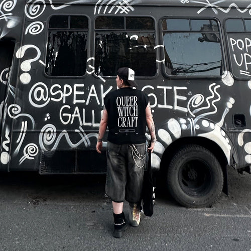 Lesbian wearing wide leg snow washed baggy shorts and a Queer Witch Craft Unholy Nova Edge Threads Black French Terry Boxy Tank Top