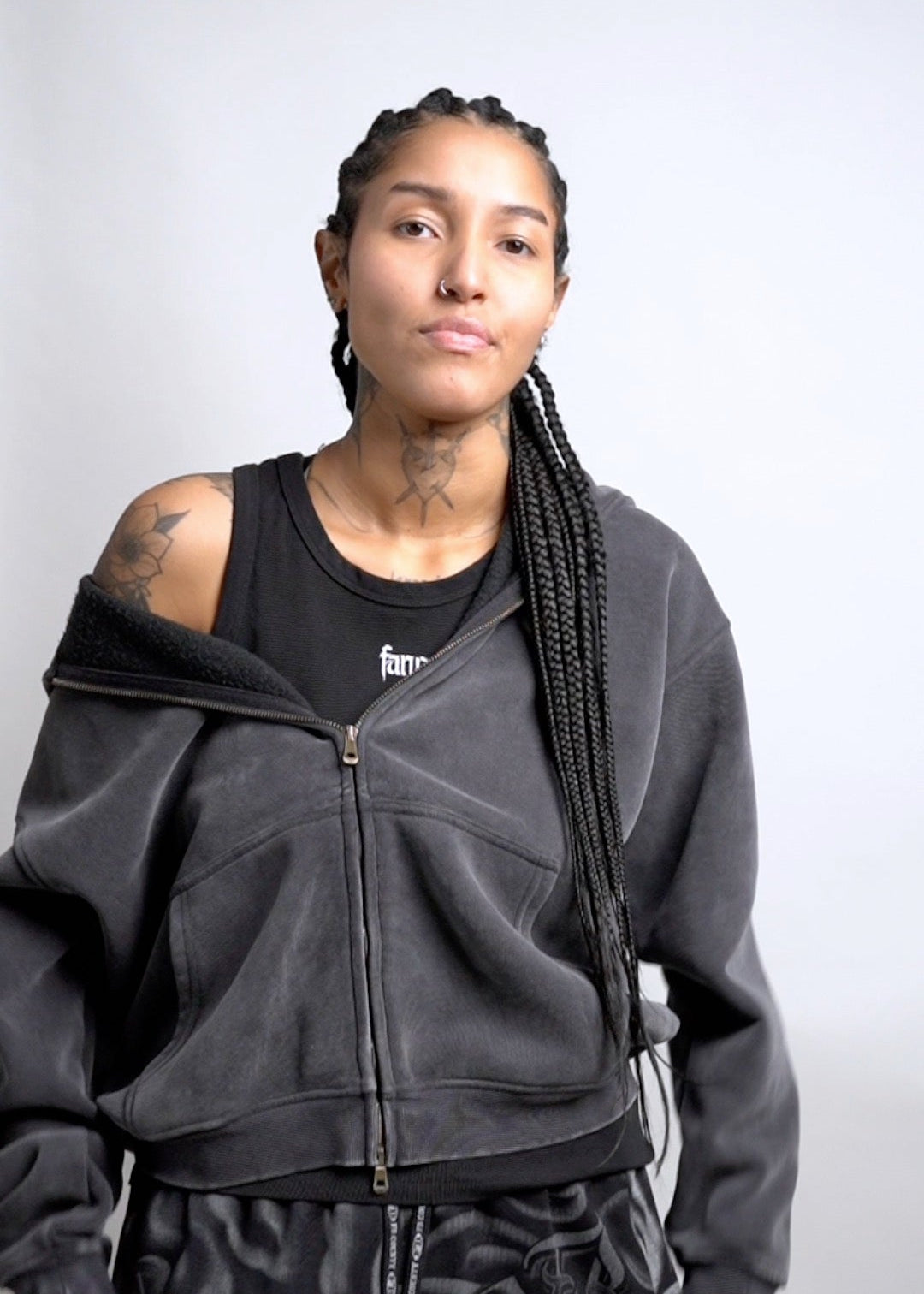 Person wearing a black tracksuit with a plain background